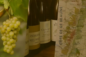 Cacho de uvas brancas ao lado de garrafas de vinho com rótulos tradicionais e mapa da região “Côte de Beaune”, destacando a origem e a identidade dos vinhos franceses