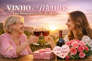 Duas mulheres brindando com taças de vinho tinto ao pôr do sol, cercadas por rosas e um presente com cartão “Feliz Dia das Mães”, representando a união entre VINHO e MULHER em celebração ao Dia das Mães